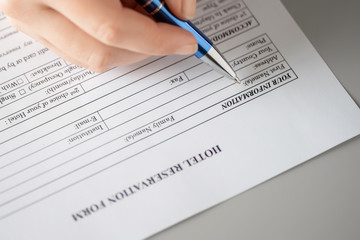 Obraz premium Woman filling hotel reservation form putting first name. Reception desk. Hotel service, registration. Close up. Selective focus.