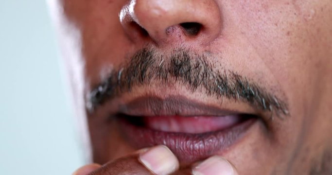 Person touching mouth thinking, macro close-up african descent, pandemic concept dont touch your face