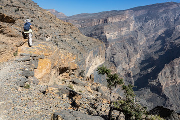 Female hiker at edge of Balcony Walk W6 above Wadi Nakhar, Jabal Shams, Oman