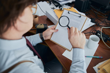 Sheriff with poor eyesight studying the documents in his office