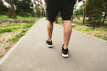 Sportsman running walking in the park, back view of legs