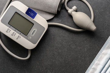 blood pressure monitor with medical disposable mask on a dark table