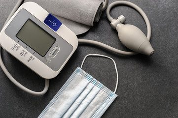blood pressure monitor with medical disposable mask on a dark table
