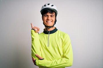 Young handsome cyclist man wearing security bike helmet over isolated white background with a big smile on face, pointing with hand and finger to the side looking at the camera.