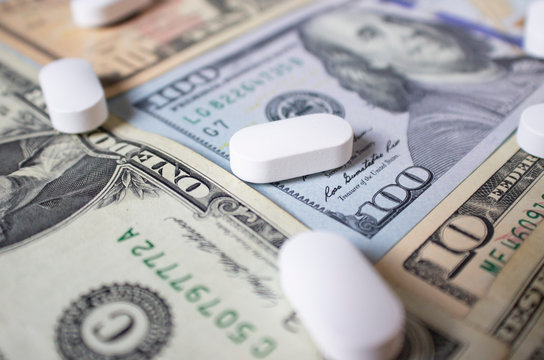White big pills on a hundred dollar bill. The concept of health insurance and healthcare costs.