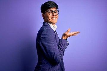 Young handsome business man wearing jacket and glasses over isolated purple background pointing aside with hands open palms showing copy space, presenting advertisement smiling excited happy