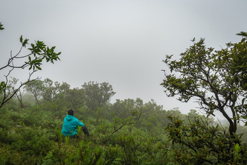 hiker resting at hilltop with breathtaking mountain layers in background