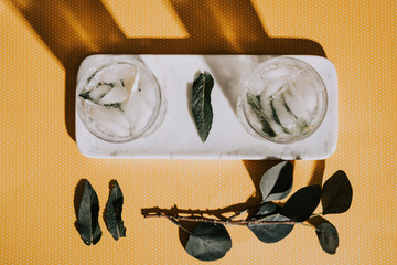 Fresh mojito alcoholic cocktail with rum, lime, mint and ice in a top shot glass shot with hard lights on yellow dots background and marble. Vintage edit  and feel