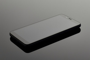 Black mobile smartphone on the surface with reflection