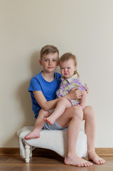 Portrait of two pretty cute children boy and girl.  Big brother holding his toddler sister. Kid sibling