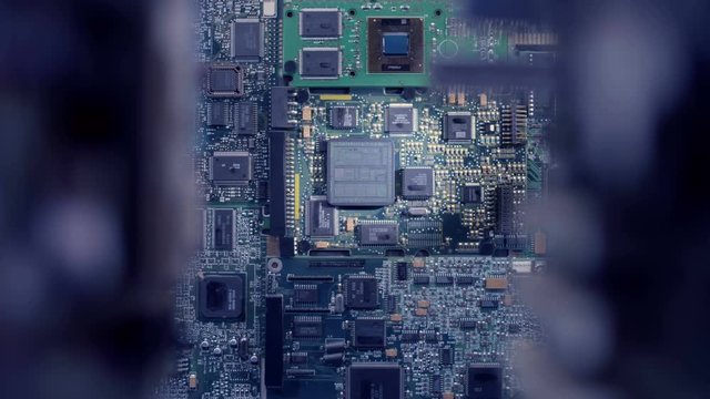 The main processor on the large board is connected to other circuits via wires glowing with blue light. Closeup