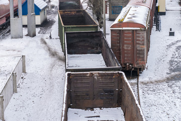 Obraz premium Empty freight cars are at the train station. Old emergency wagons rust under the snow. View from above. Industrial Transport Concept