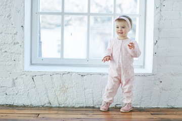 a little girl stands near the window and smiles