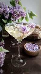 Glass of champagne with ice on a lilac background