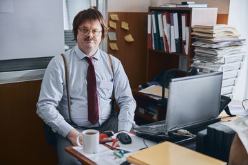 Middle-aged male person making break in his paperwork