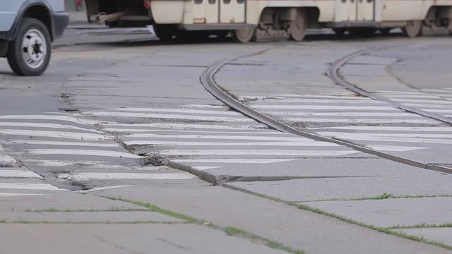 Poor condition of the road surface with tramway rails. Cars crossing dangerous road with potholes in asphalt. Intersection before reconstruction