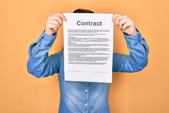 Woman holding contract document paper standing over isolated yellow background