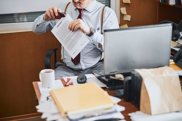Old-fashioned man joining parts of a contract together with stapler