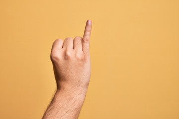 Hand of caucasian young man showing fingers over isolated yellow background showing little finger as pinky promise commitment, number one