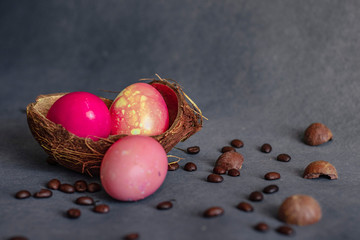 Easter eggs in a coconut shell on a gray background with coffee beans around
