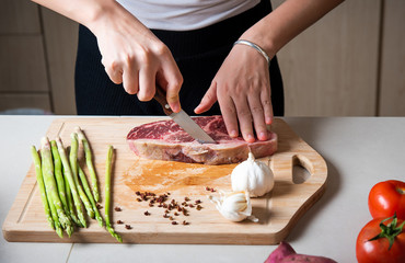 Woman cutting Wagyu Japanese beef steak on the cutting board
