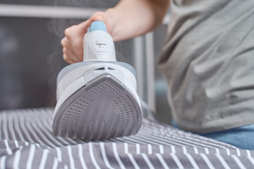 Steam boost on the modern iron. Woman ironing clothes with modern iron
