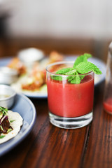 Strawberry juice with mint on top, next to food on a table in a cafe
