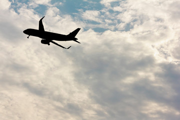 Silhouette plane flying in cloud of the clouds in background