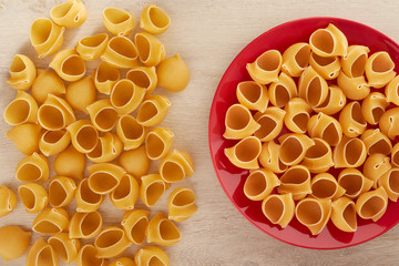 Raw pasta on a red plate, top view