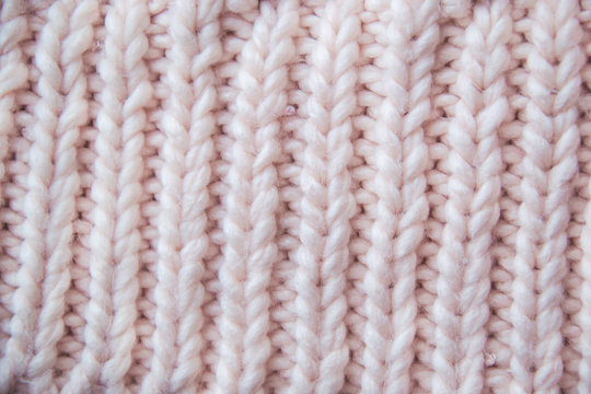 Marco picture of knitted pattern which located on sweater in pink shade with nude undertone as home made hobby concept with clothings for winter and stylish design of natural yarns background