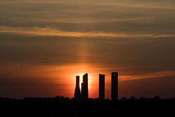 Red sun coming out behind the four towers on silhouette. Beautiful dark sunrise Madrid.