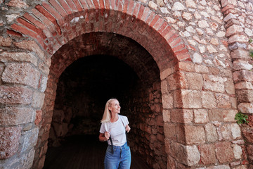 Fototapeta na wymiar Young traveling woman with rucksack walking in ancient fortress.