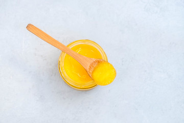 Fototapeta na wymiar Jar of healthy ghee butter with spoon on neutral background