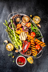Hot vegetable salad. Set different grilled vegetables on a plate. Vegan barbeque picnic set, with asparagus, tomatoes, mushrooms, peppers, corn and sauces