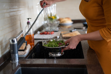 Girl washes the ingredients for the salad in the sink. Careful hygiene of products. Fresh clean arugula leaves