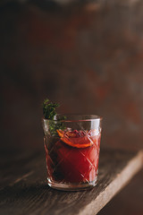 Old-fashioned cocktail with blood oranges and thyme on the rustic background. Selective focus. Shallow depth of field.