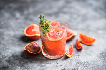 Old-fashioned cocktail with blood oranges and thyme on the rustic background. Selective focus. Shallow depth of field.