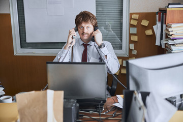 Aged office clerk is shocked answering two calls at one time
