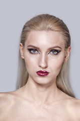 Portrait of a blonde with bright eye and lip makeup. A look into the camera.