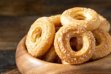 Puff pastry sprinkle with sugar in a wooden bowl on a brown wooden background. Cookies sprinkle with sugar close-up. Sweet pastries