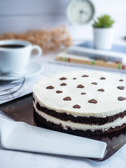 white chocolate layer cake , decorated with egg whisk , coffee cup and bouquet of flowers, selective focus. fresh homemade bakery concept