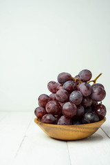 Blue grapes on white wooden background.