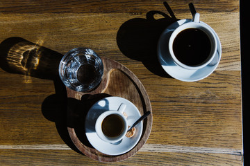 Two cups of coffee on a table in the sun.
