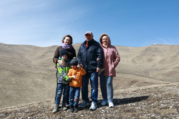 Obraz na płótnie Canvas Family posing on rocky ridge of Caucasus background