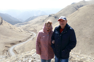 Obraz na płótnie Canvas Senior couple on rocky ridge of Caucasus background