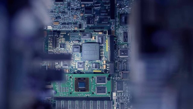 The main processor on the large board is connected to other circuits via wires glowing with blue light. Closeup