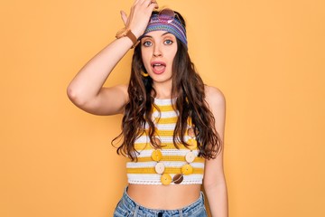 Young beautiful hippie woman with blue eyes wearing accesories and sunnglasses surprised with hand...