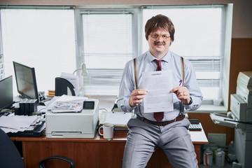 Smiling aged corporate worker holding an important document he worked with - obrazy, fototapety, plakaty