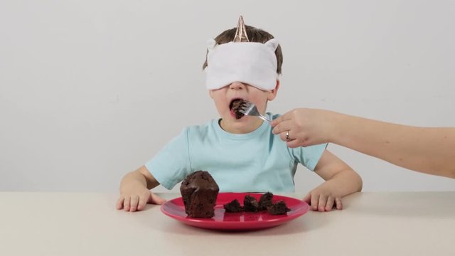 Little boy in a mask tries and guesses chocolate muffin