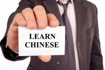 Man holding a card on which is written learn Chinese
